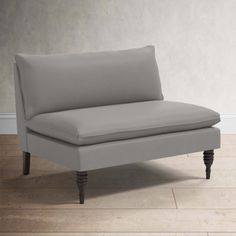 a gray couch sitting on top of a hard wood floor next to a white wall