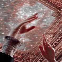 two hands reaching up towards the ceiling in a room with stars and lights on it