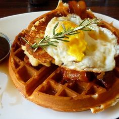 a waffle topped with bacon and eggs on a white plate