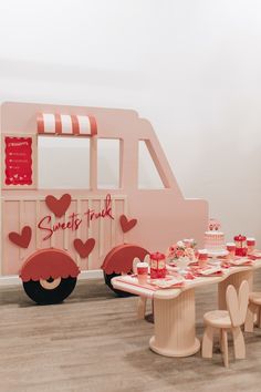 a table and chairs are set up in front of a pink truck with hearts on it