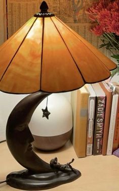 a lamp that is sitting on top of a table next to some books and a vase