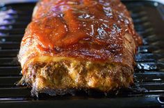 a piece of meat covered in bbq sauce sitting on top of a black grill