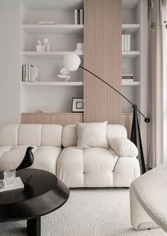 a living room filled with white furniture and bookshelves