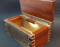 an open wooden box with drawers on the top and bottom, sitting on a blue surface