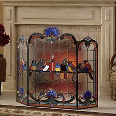 an ornate fireplace screen with birds painted on it's sides and in front of a fire place