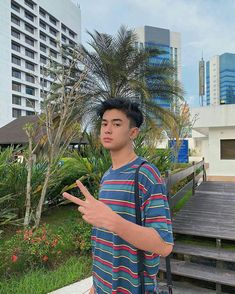 a young man is standing in front of some buildings and pointing at something with his hand