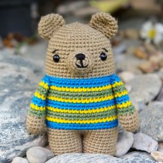 a crocheted teddy bear wearing a striped shirt