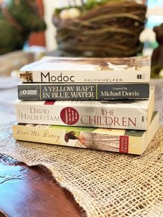 three books stacked on top of each other in front of a basket filled with flowers