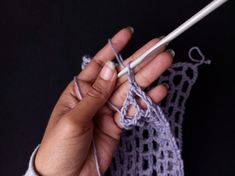 a woman is knitting with two crochet hooks