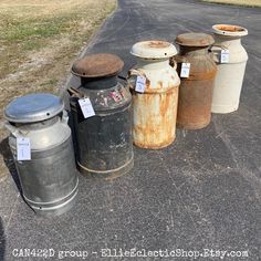 an assortment of old metal containers sitting on the side of a road with tags attached to them