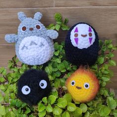 four crocheted toy animals sitting on top of green plants with eyes drawn on them