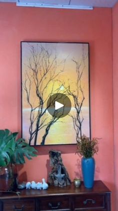 a painting hanging on the wall next to a wooden table with vases and plants