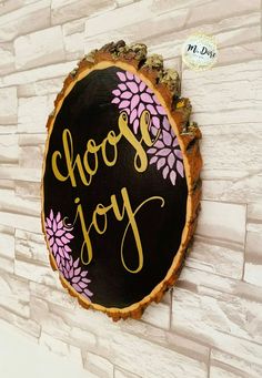 a wooden sign that says choose joy on the side of a brick wall with flowers