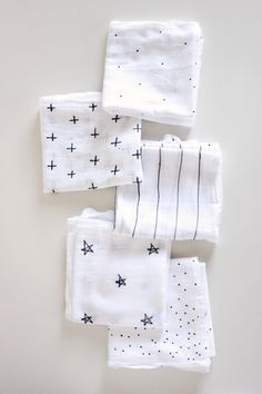 four white napkins with black crosses on them sitting on top of each other in front of a white wall