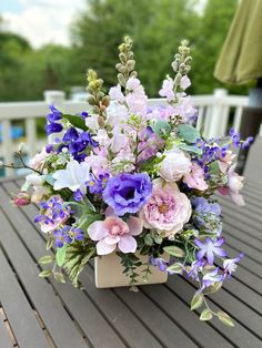 a vase filled with lots of purple and white flowers on top of a wooden table