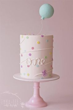 a white cake with polka dots and a balloon on top