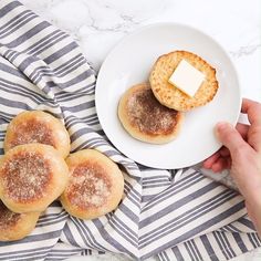 a person holding a plate with some cookies and butter on it next to another plate