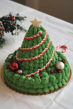 a decorated christmas tree cake sitting on top of a white table covered in green frosting