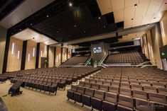 an empty auditorium filled with brown chairs