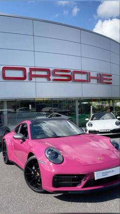 a pink porsche parked in front of a porsche dealership