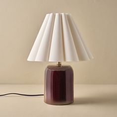 a table lamp with a white shade on it and a cord plugged into the base