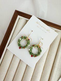 a pair of green and red beaded earrings sitting on top of a white card