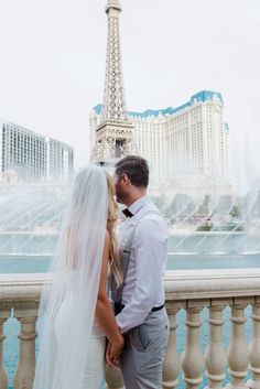 a bride and groom standing next to the eiffel tower in paris, france