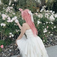 a woman with pink hair is sitting in front of flowers