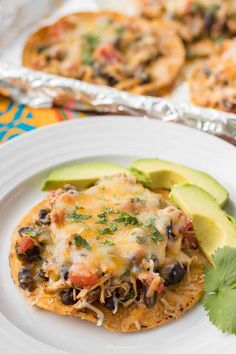 an enchilada on a plate with avocado and cilantro