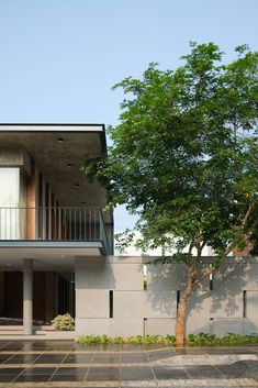 a large white building with a tree in front of it and two balconies on the second floor