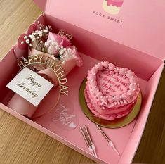 a pink birthday cake in a pink box with flowers on the table next to it