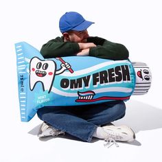 a man sitting on the ground with a giant inflatable pillow that says, only fresh