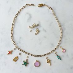 a gold chain bracelet with various charms attached to it on a white marble countertop