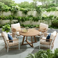 an outdoor table and chairs with plants on the wall in the backround area