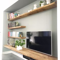 a flat screen tv sitting on top of a wooden shelf next to a book shelf