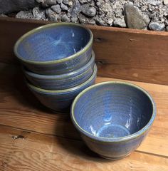 four blue bowls are stacked on top of each other in front of a pile of rocks