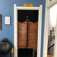 an open door leading into a room with a black chair and pictures on the wall