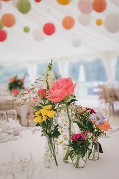 two vases with flowers are sitting on a table in front of a white tent