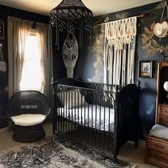 a black and white nursery room with an iron crib in the corner, hanging decorations on the wall