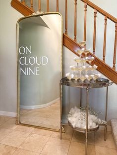 a table with cupcakes on it next to a mirror and stairs that says on cloud nine