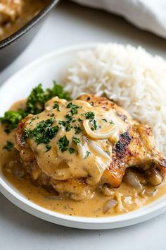 a white plate topped with meat covered in gravy next to rice and broccoli