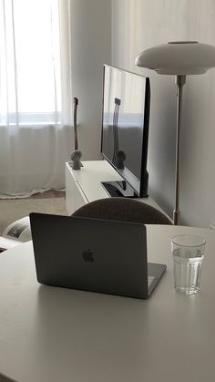 a laptop computer sitting on top of a white table in front of a tv set