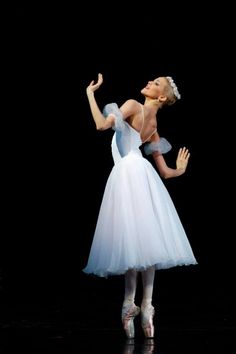 a woman in a white dress is performing on stage