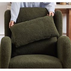 a person holding a pillow on top of a green chair