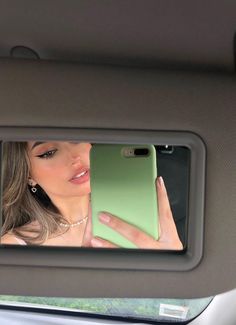 a woman taking a selfie in the back seat of a car with her cell phone