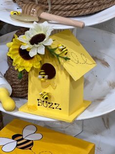 a yellow birdhouse with flowers and bees on it