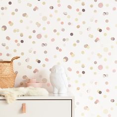 a white dresser sitting next to a wall covered in polka dots