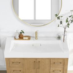 a bathroom with a round mirror above the sink and wooden cabinets below it, along with a plant