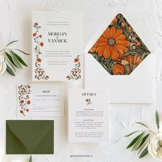 wedding stationery with orange flowers and greenery on white paper, along with matching envelopes