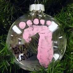 a glass ornament with a pink handprinted baby's foot on it